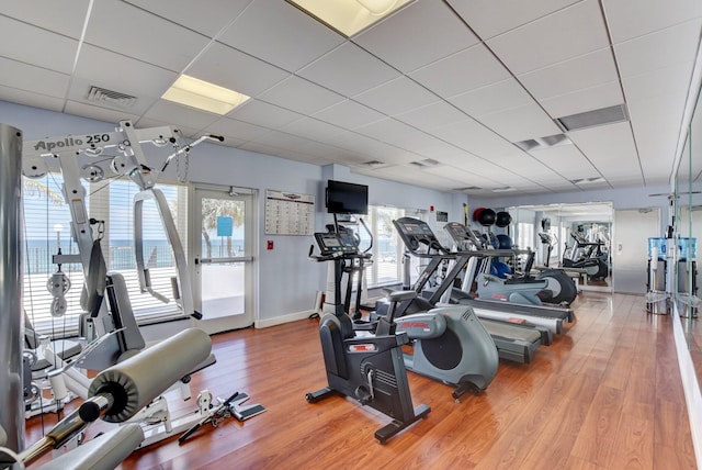 gym with hardwood / wood-style floors and a paneled ceiling