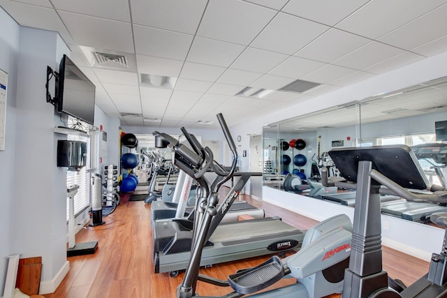 workout area with a paneled ceiling and wood-type flooring