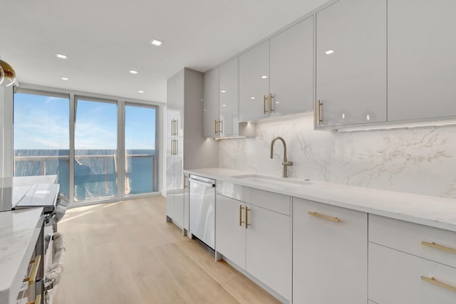 kitchen with white cabinetry, sink, light stone counters, a water view, and appliances with stainless steel finishes