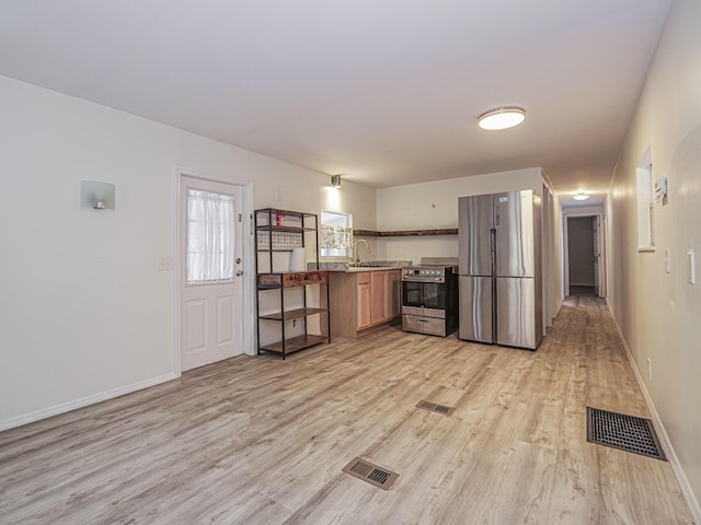 kitchen featuring stainless steel appliances, visible vents, light wood-style floors, a sink, and baseboards