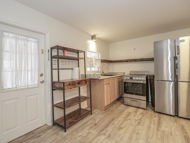 kitchen with a sink, appliances with stainless steel finishes, light stone countertops, open shelves, and light wood finished floors