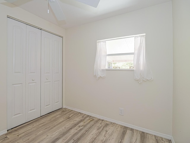 unfurnished bedroom featuring a closet, ceiling fan, light wood-style flooring, and baseboards