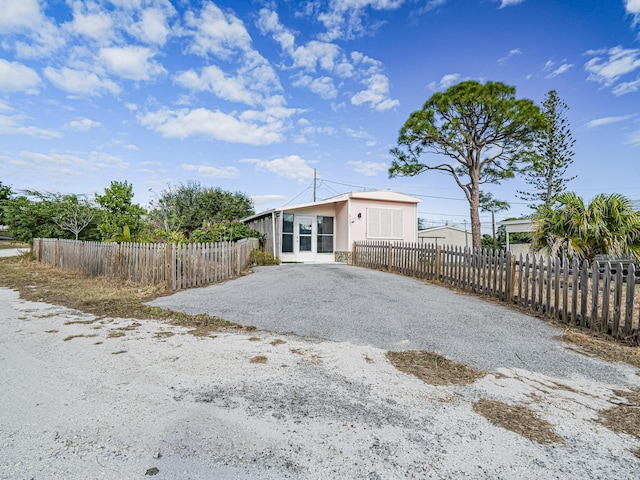 exterior space with gravel driveway, a fenced front yard, and stucco siding