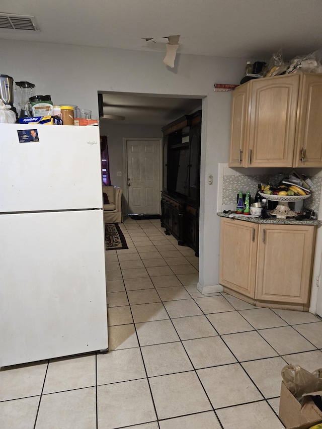 kitchen featuring tasteful backsplash, light brown cabinets, white fridge, and light tile patterned floors