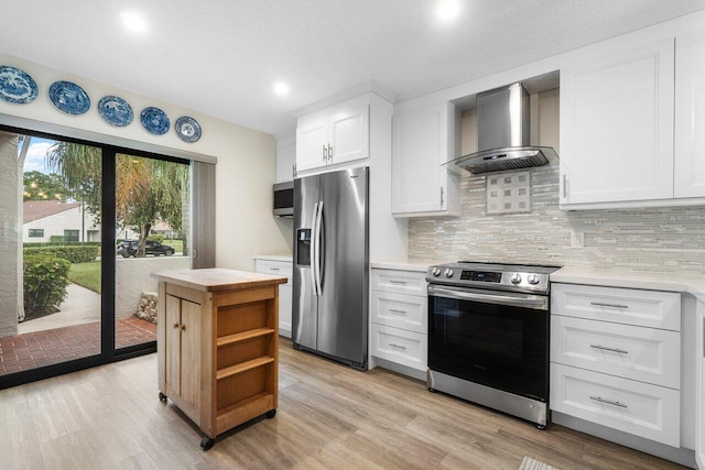 kitchen featuring white cabinetry, stainless steel appliances, wall chimney range hood, tasteful backsplash, and light wood-type flooring