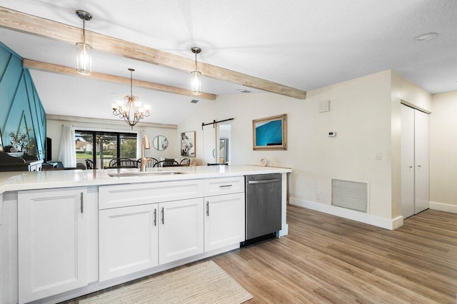 kitchen with stainless steel dishwasher, sink, a barn door, white cabinets, and hanging light fixtures