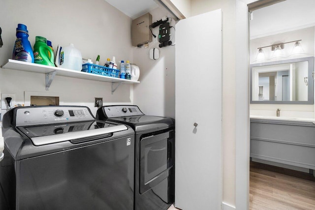 laundry area featuring washer and clothes dryer, light hardwood / wood-style floors, and sink