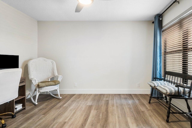 living area featuring ceiling fan, hardwood / wood-style floors, and a textured ceiling