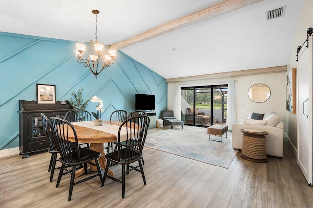 dining room featuring vaulted ceiling with beams, a barn door, an inviting chandelier, and light hardwood / wood-style flooring