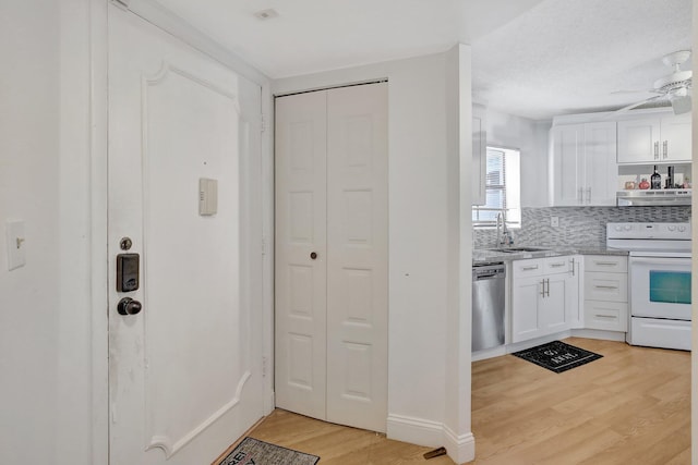 kitchen featuring white electric range, white cabinetry, stainless steel dishwasher, and range hood