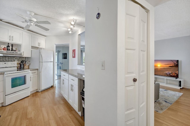 kitchen with light stone countertops, light wood-type flooring, white appliances, a textured ceiling, and white cabinets