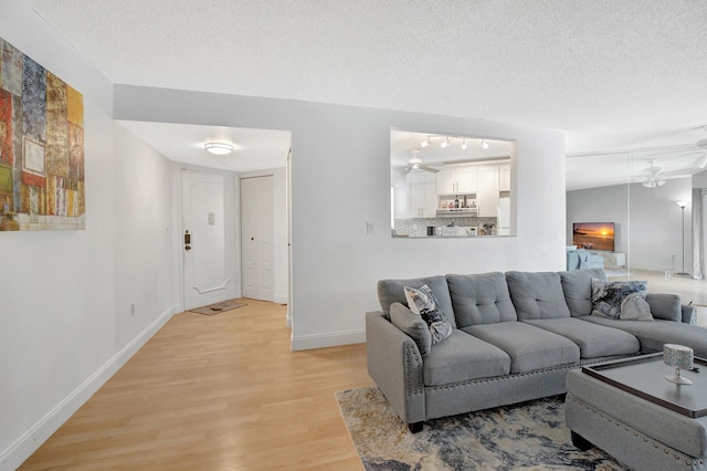 living room featuring a textured ceiling, light hardwood / wood-style floors, and ceiling fan