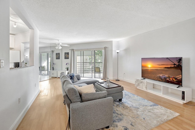 living room with ceiling fan, a textured ceiling, and light hardwood / wood-style flooring