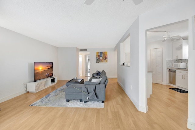 living room featuring a textured ceiling, light hardwood / wood-style flooring, and ceiling fan