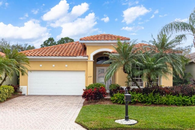 mediterranean / spanish-style home featuring a front yard and a garage