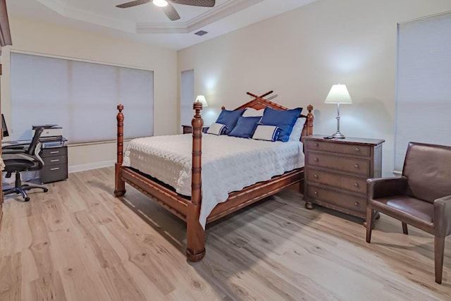 bedroom featuring visible vents, a tray ceiling, ceiling fan, light wood-style floors, and a closet