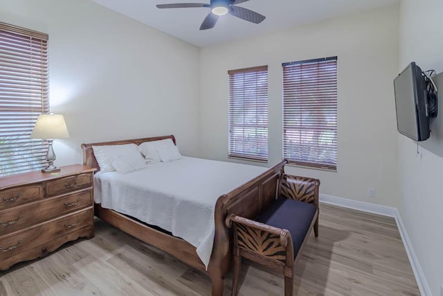 bedroom with light wood finished floors, a ceiling fan, and baseboards