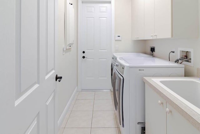 laundry area featuring independent washer and dryer, a sink, cabinet space, light tile patterned floors, and baseboards