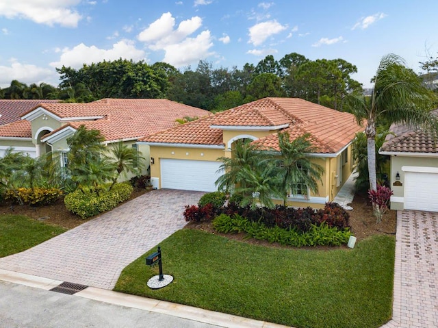 mediterranean / spanish home with a garage, stucco siding, a tile roof, and a front yard