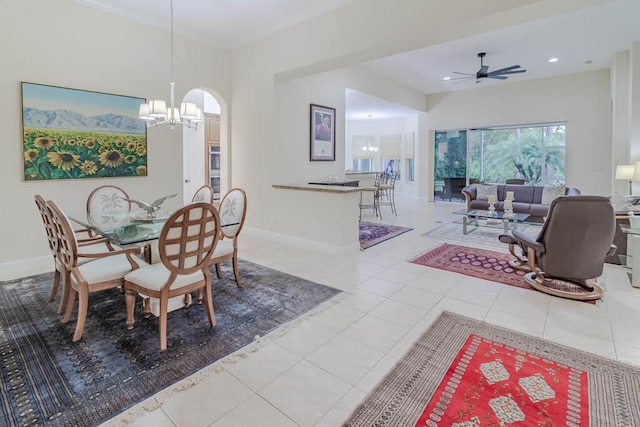 dining room featuring tile patterned floors, ceiling fan with notable chandelier, recessed lighting, arched walkways, and baseboards