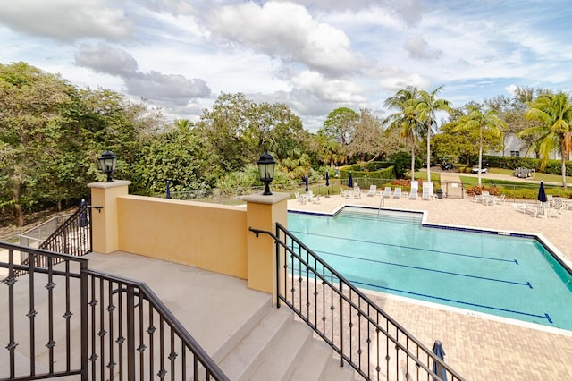 pool with stairs, a patio, and fence