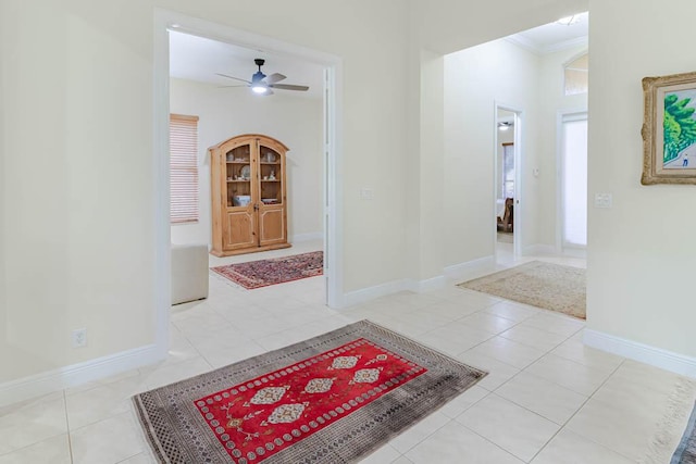 corridor featuring light tile patterned flooring, baseboards, and ornamental molding