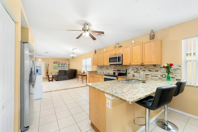 kitchen with sink, kitchen peninsula, a kitchen bar, decorative backsplash, and appliances with stainless steel finishes