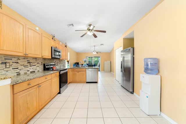 kitchen featuring light stone countertops, tasteful backsplash, kitchen peninsula, light tile patterned floors, and appliances with stainless steel finishes