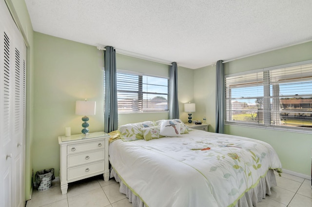 bedroom with light tile patterned floors, a textured ceiling, and a closet