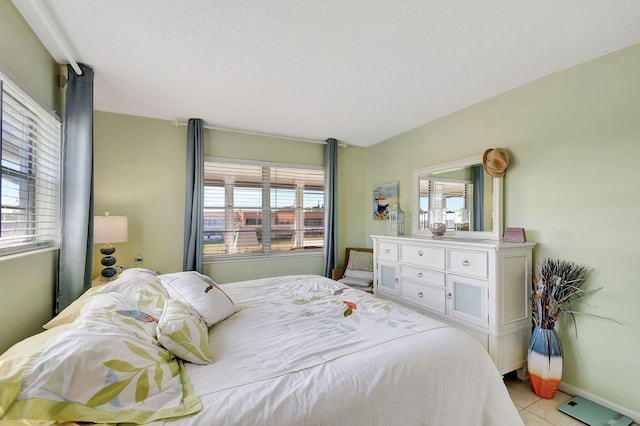 tiled bedroom with a textured ceiling and multiple windows