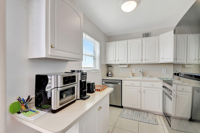 kitchen with white cabinets, light tile patterned floors, sink, and appliances with stainless steel finishes