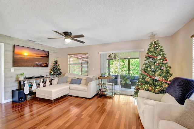 living room featuring ceiling fan, hardwood / wood-style floors, and a textured ceiling