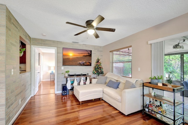 living room with a textured ceiling, hardwood / wood-style flooring, ceiling fan, and a healthy amount of sunlight