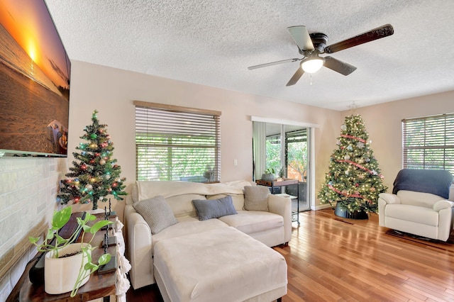 living room featuring a textured ceiling, light hardwood / wood-style floors, and ceiling fan