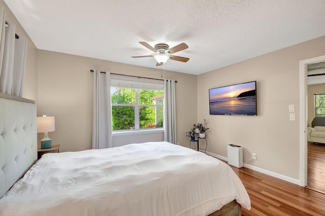 bedroom featuring hardwood / wood-style floors, ceiling fan, and a textured ceiling