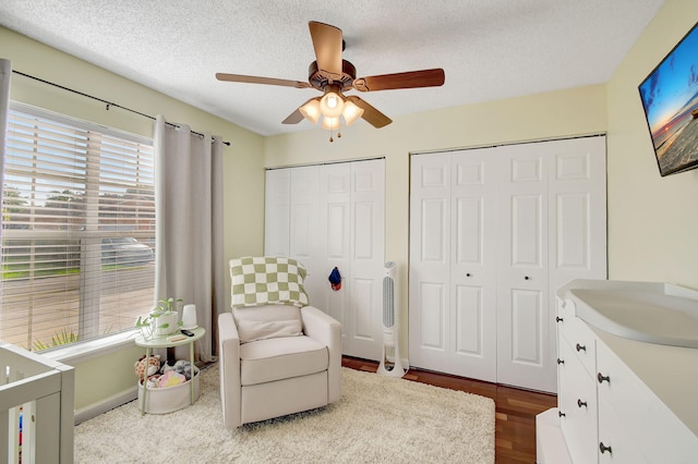 bedroom featuring hardwood / wood-style floors, a textured ceiling, two closets, and ceiling fan