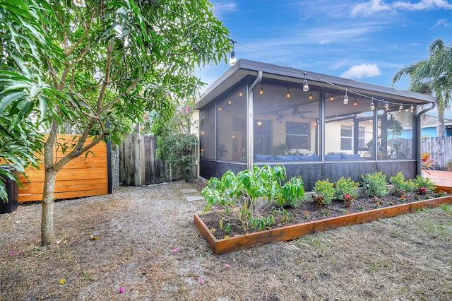 view of yard featuring a sunroom and ceiling fan