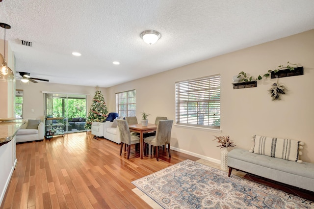 dining area with ceiling fan, a textured ceiling, and light hardwood / wood-style flooring