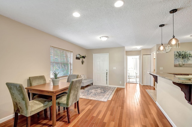 dining area featuring a textured ceiling and light hardwood / wood-style flooring