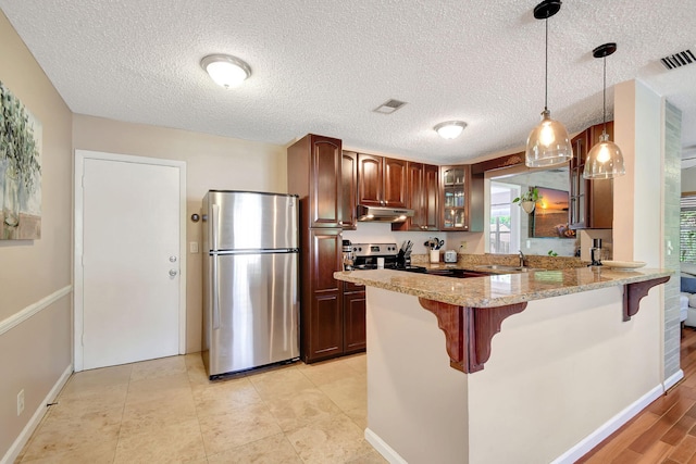 kitchen with sink, hanging light fixtures, light stone countertops, a textured ceiling, and stainless steel appliances