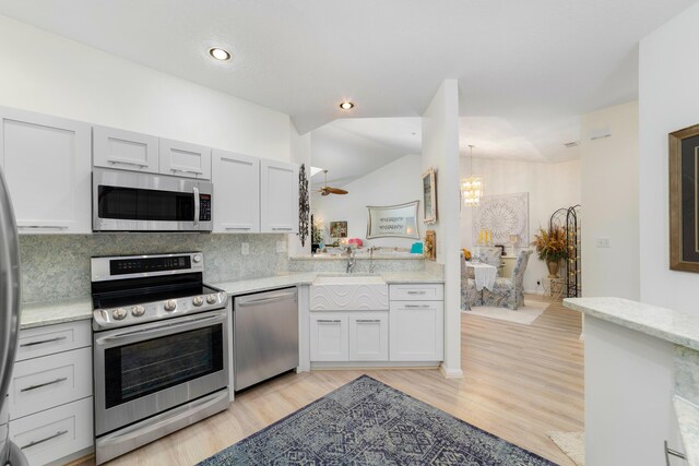 kitchen with pendant lighting, sink, light hardwood / wood-style floors, light stone counters, and white cabinetry