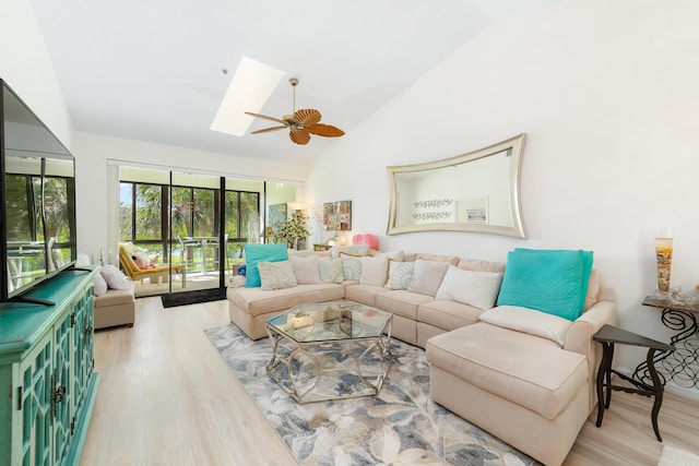 living room featuring ceiling fan, wood-type flooring, high vaulted ceiling, and a skylight