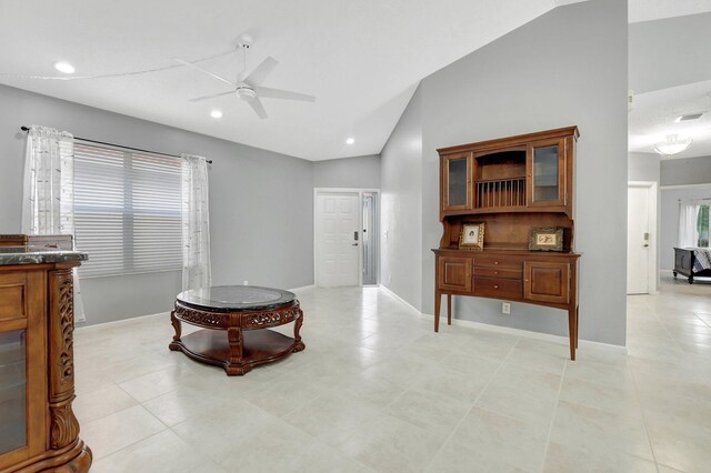 living room with ceiling fan, plenty of natural light, light tile patterned floors, and vaulted ceiling