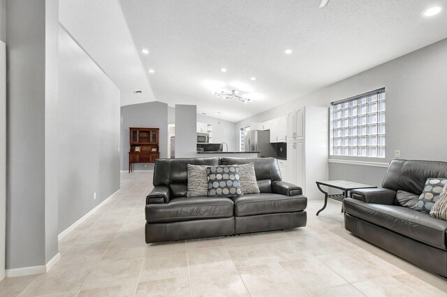 living room featuring ceiling fan, light tile patterned flooring, a textured ceiling, and vaulted ceiling