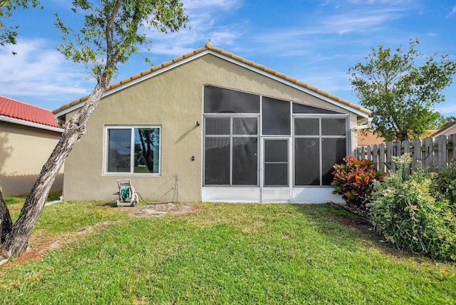 rear view of property featuring a sunroom and a lawn