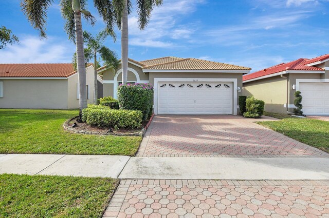 mediterranean / spanish-style house featuring a front yard and a garage