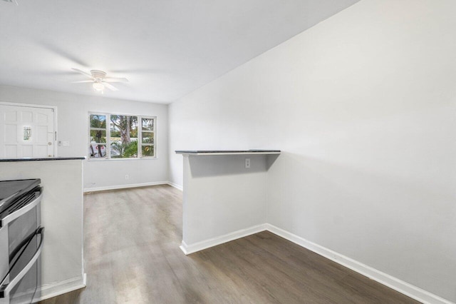 kitchen with stainless steel range, kitchen peninsula, ceiling fan, and hardwood / wood-style floors