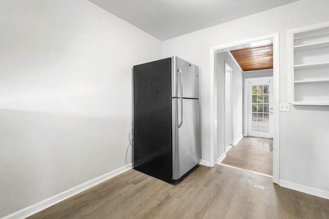 kitchen with stainless steel fridge, light hardwood / wood-style floors, and wooden ceiling