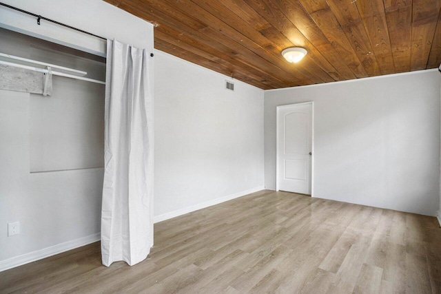 unfurnished bedroom with light hardwood / wood-style floors, wood ceiling, and a closet