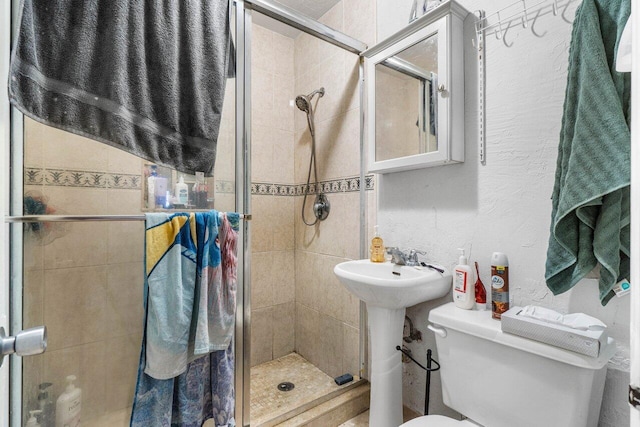 bathroom with sink, a shower with door, and toilet